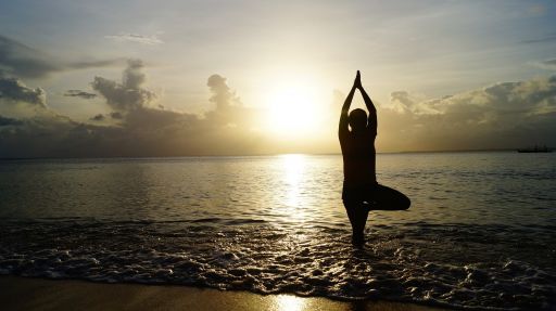 Prostata Hilfe Deutschland: Symbolbild für Yoga bei Prostatakrebs - Mensch steht bei Sonnenuntergang am Strand und macht eine Yogapose